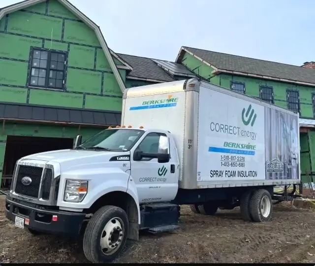 The Correct Energy box truck parked at an active job site, house wrap and framing visible behind it